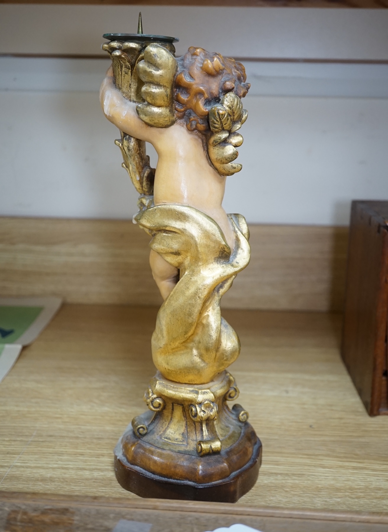 An Austrian carved and partially gilt cherub pricket candlestick, 37cm high. Condition - fair to good